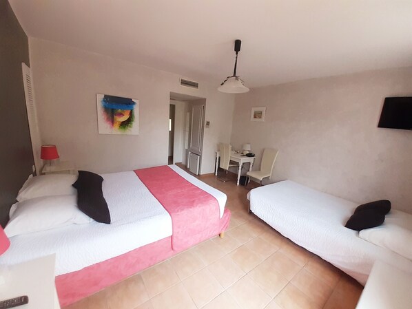A hotel room with two beds, a desk, a chair, a lamp, and a painting on the wall. - Hôtel Restaurant Le Clos Des Capitelles (Uchaud)