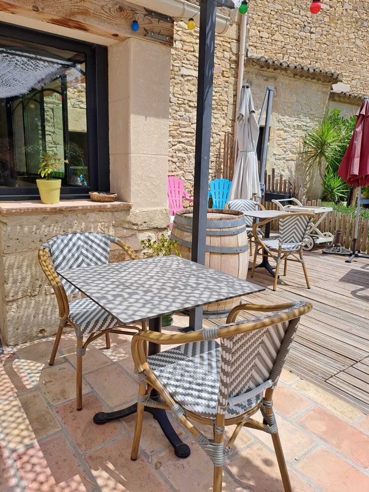 Un patio al aire libre con mobiliario de mimbre, una pared de piedra y una ventana con planta en maceta.