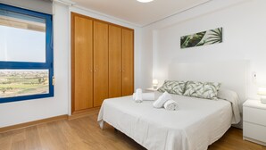 Un dormitorio con cama, armario de madera, ventana con vistas y una obra de arte en la pared.