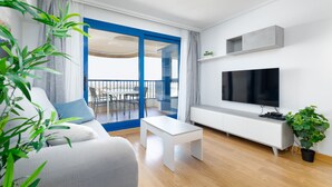 Una sala de estar moderna con un sofá, una mesa de centro, un televisor y un balcón con marco azul.