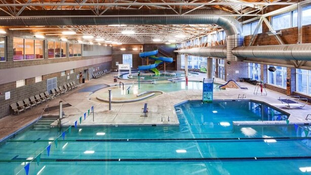 Une piscine intérieure dotée de plusieurs couloirs de nage, d’un toboggan et d’espaces aménagés pour se détendre.