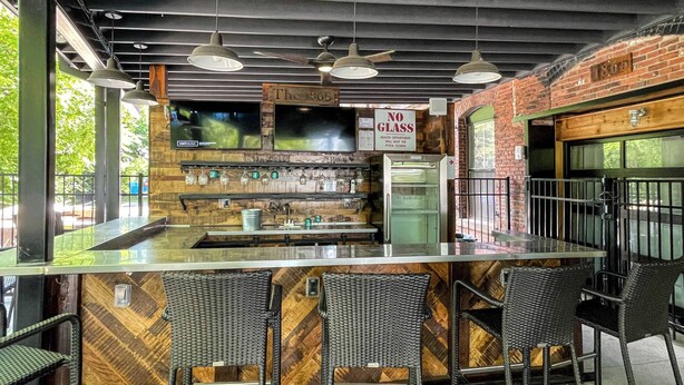 Zona de bar con mostrador de madera, tres sillas de mimbre y un letrero que indica 'No Glass'.