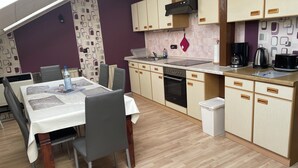 Eine moderne Küche mit Holzausstattung, einem Einbauofen und einem Essbereich mit Tisch und Stühlen.
