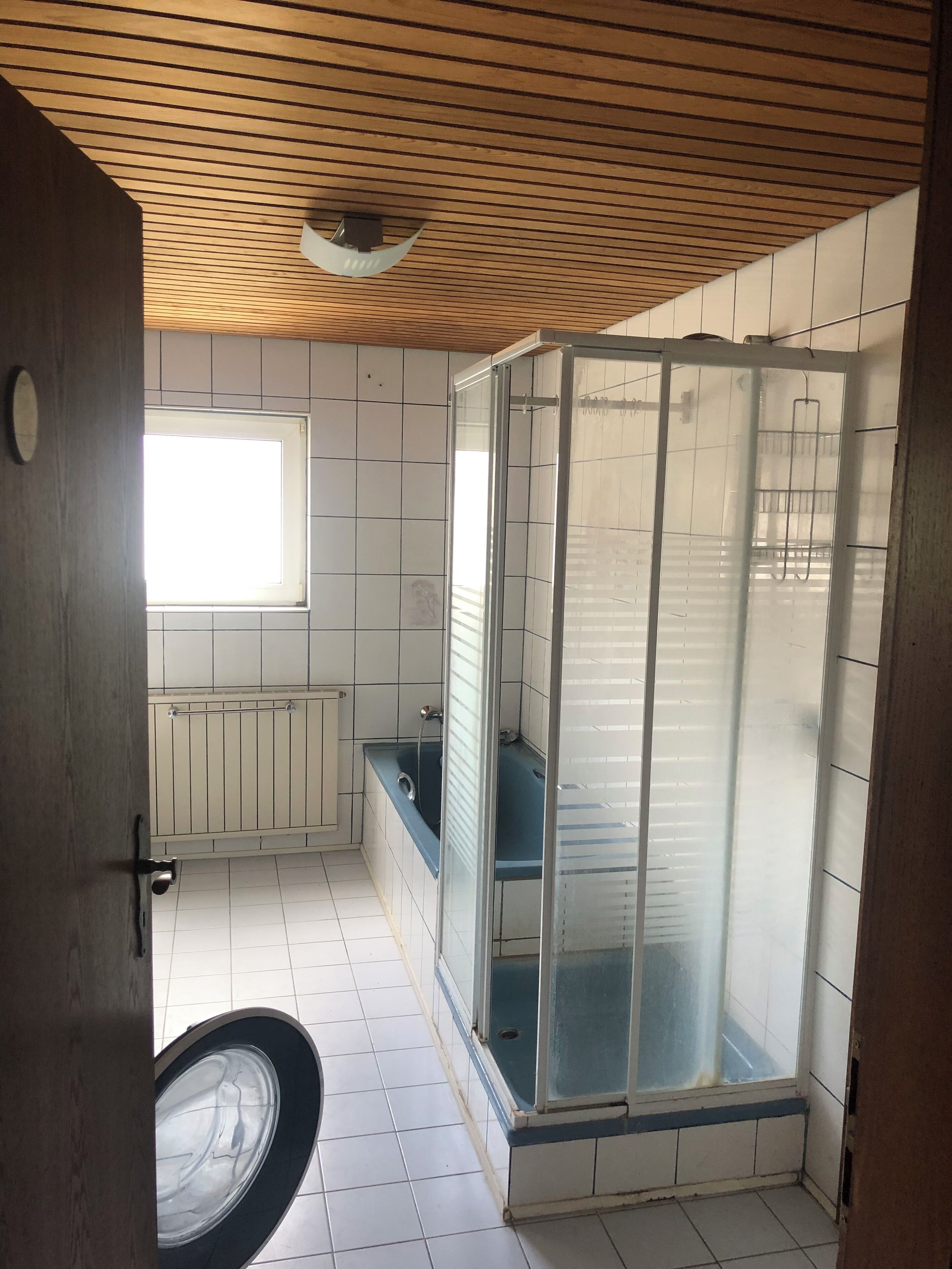 A bathroom with a shower enclosure, a window, and a toilet.
