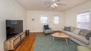 A living room with a TV, sofa, coffee table, and a ceiling fan. - Cityscape Escape (Cincinnati)