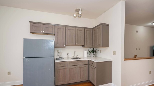 A kitchen with wooden cabinets, a refrigerator, a sink, and a countertop. - Cityscape Escape (Cincinnati)