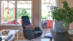 Un interior moderno con techo de madera, un comedor con mesa y sillas, y un ventanal con vistas a follaje exterior.