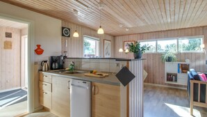 Una cocina moderna con paneles de madera, lavavajillas integrado y una isla central con tabla de cortar.