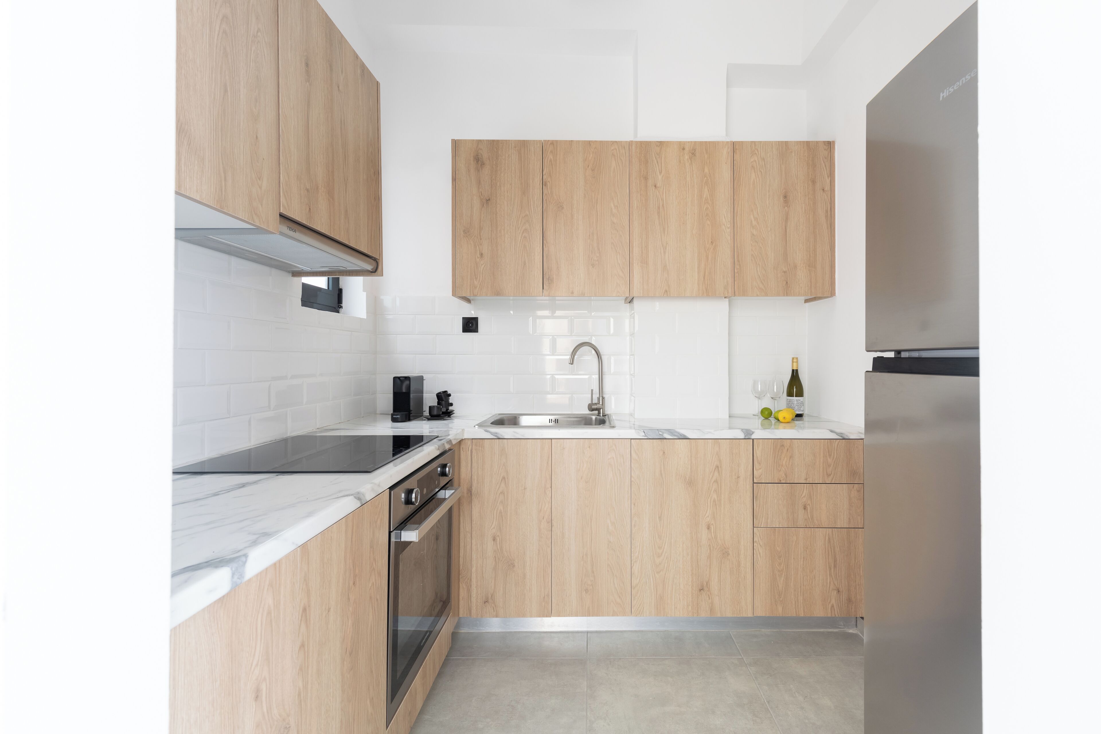 Cozinha moderna com armários de madeira, geladeira de aço inoxid ável e painel de azulejos branco.