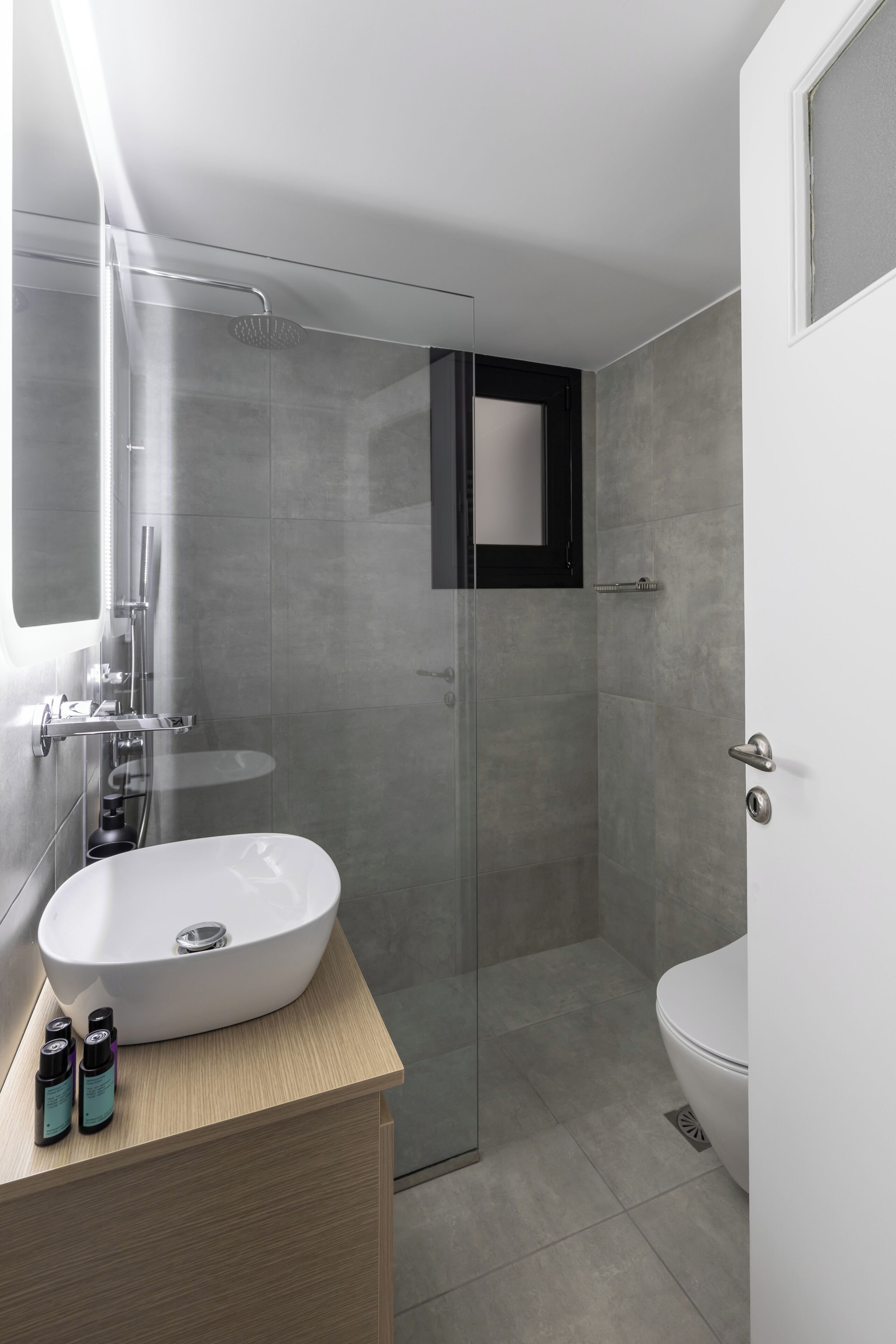 A modern bathroom with a glass-enclosed shower, a white sink, and a toilet.