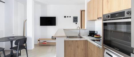 Una cocina moderna con horno empotrado, lavadora y televisor de pantalla plana montado en la pared.