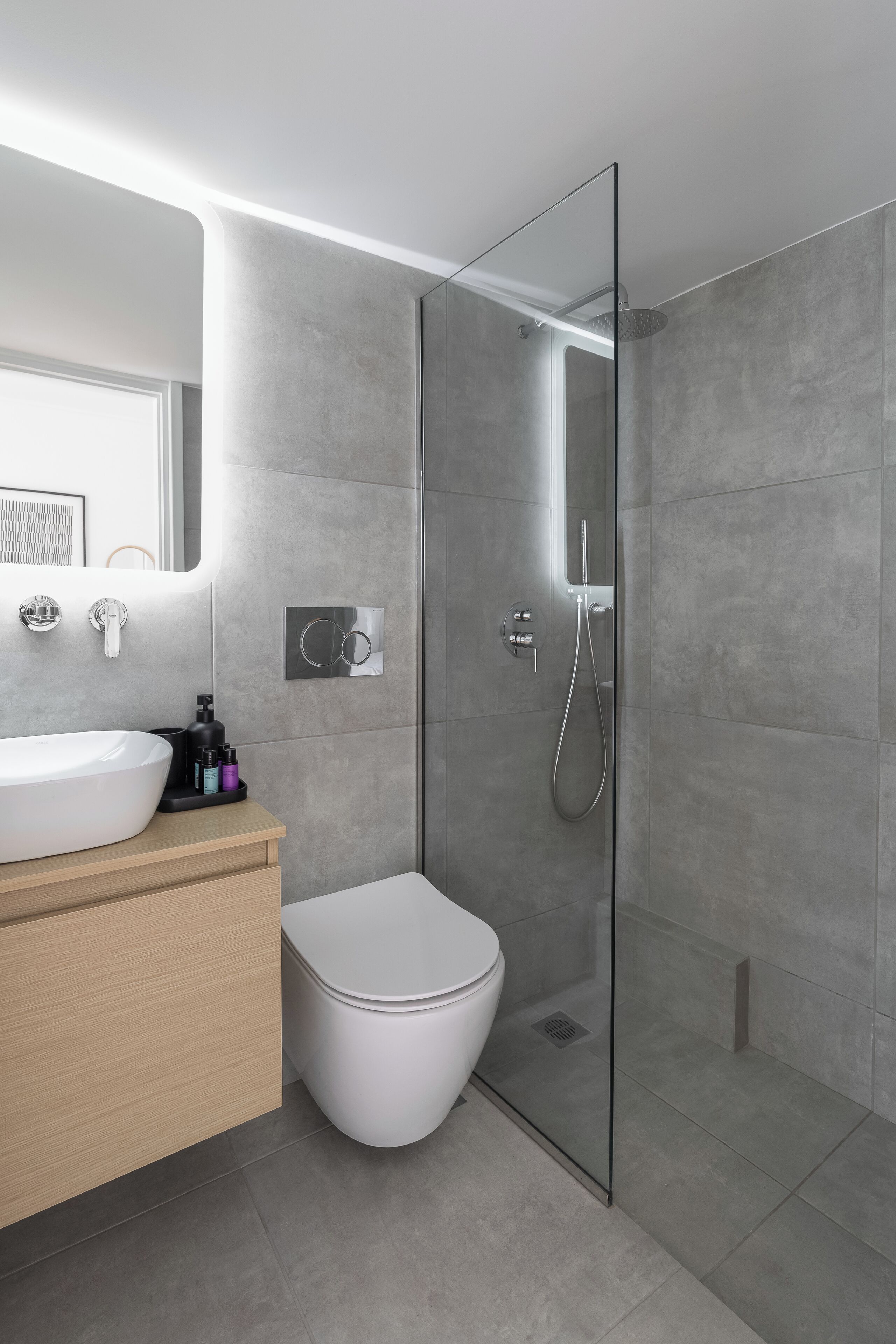 A modern bathroom with a glass-enclosed shower, a white sink, and a toilet.