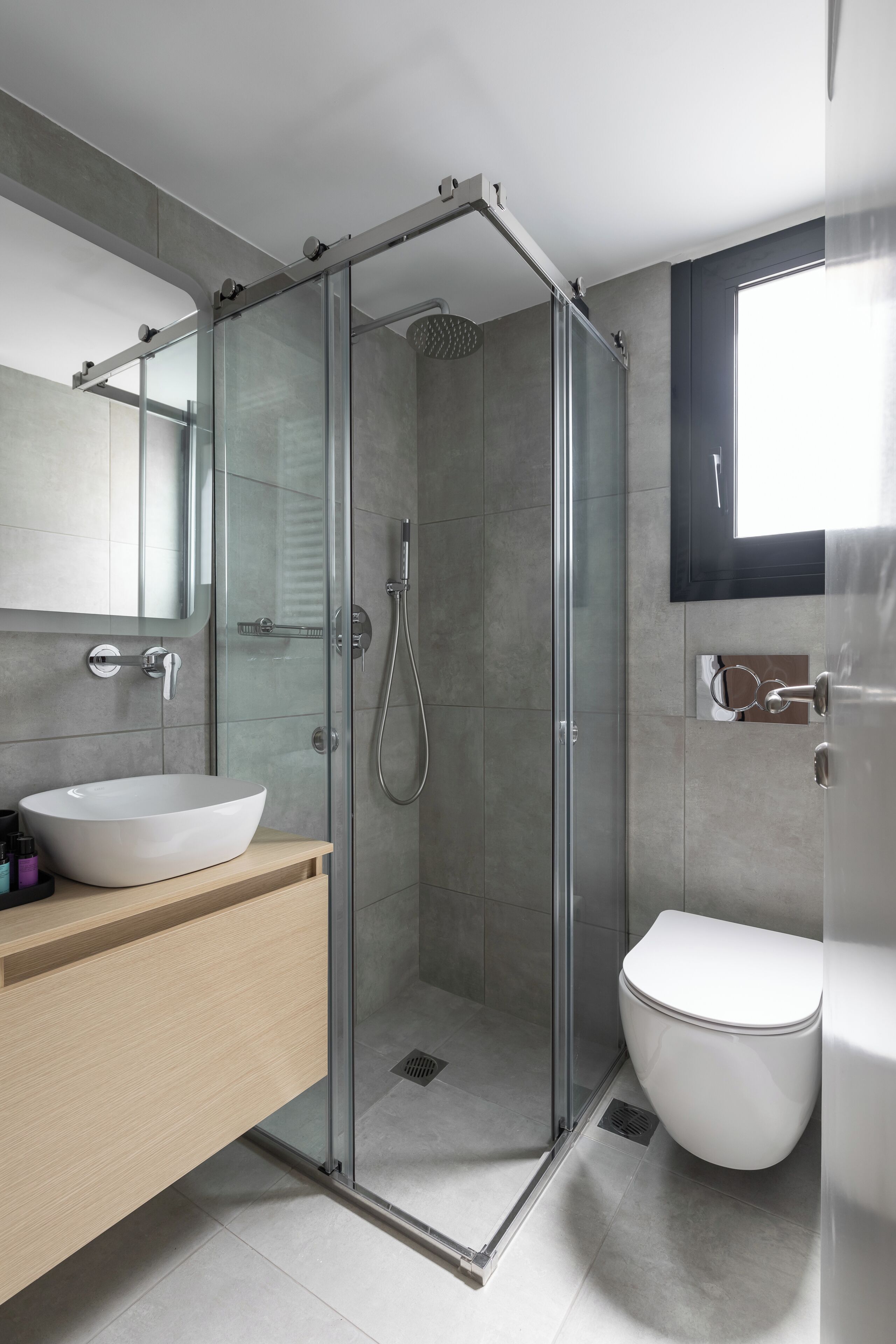 A modern bathroom with a glass-enclosed shower, a white sink, and a toilet.