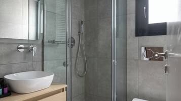 A modern bathroom with a glass-enclosed shower, a white sink, and a toilet.