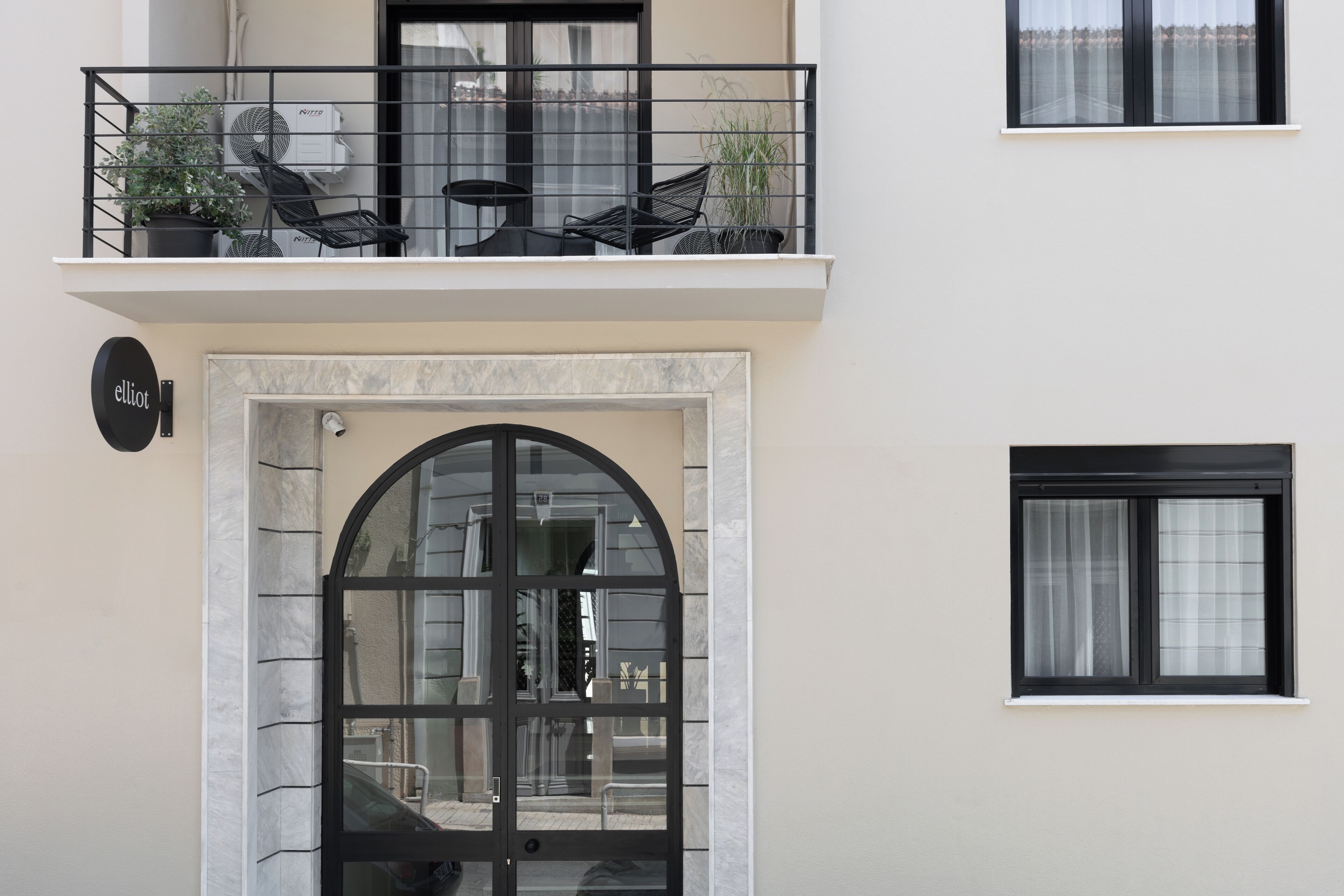 A building with a ground-level entrance, a balcony with outdoor seating, and a small window.