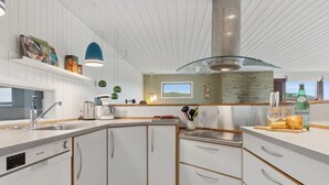 Ett modernt kök med vita köksskåp, en inbyggd diskmaskin och ett trägolv.