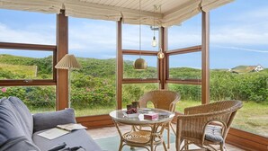 Ett uterum med ett glasbord, flätade stolar och en soffa.