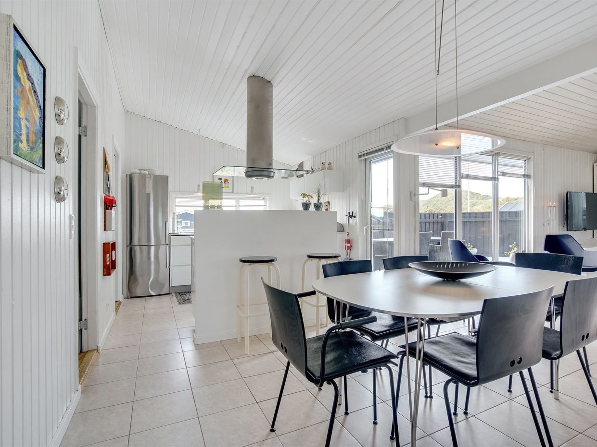 A modern kitchen with white cabinetry, a stainless steel refrigerator, and a large island with bar stools.