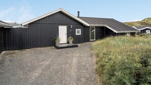 Un bâtiment en bois noir avec une porte blanche, une petite fenêtre et le chiffre « 7 » peint sur le mur.