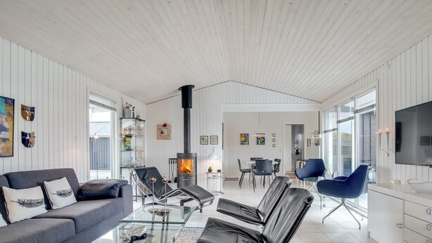 Un salon moderne avec un canapé, des fauteuils, une table basse en verre et une cheminée.