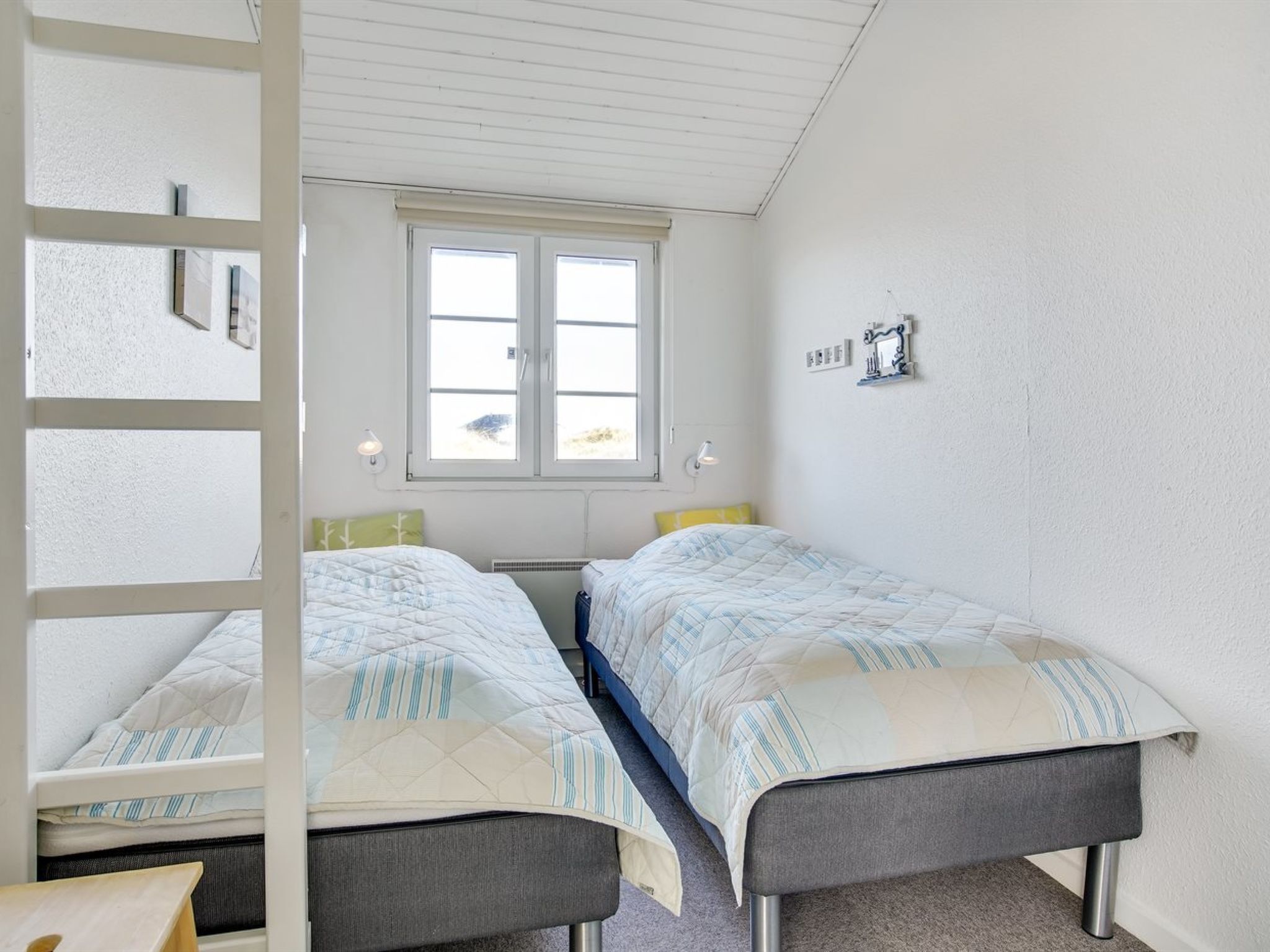 Une chambre avec deux lits, une fenêtre et un plafond blanc.