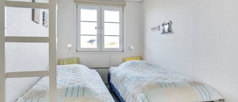 Une chambre avec deux lits, une fenêtre et un plafond blanc.