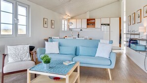 A modern living room with a light blue sofa, a coffee table, and a dining area in the background.