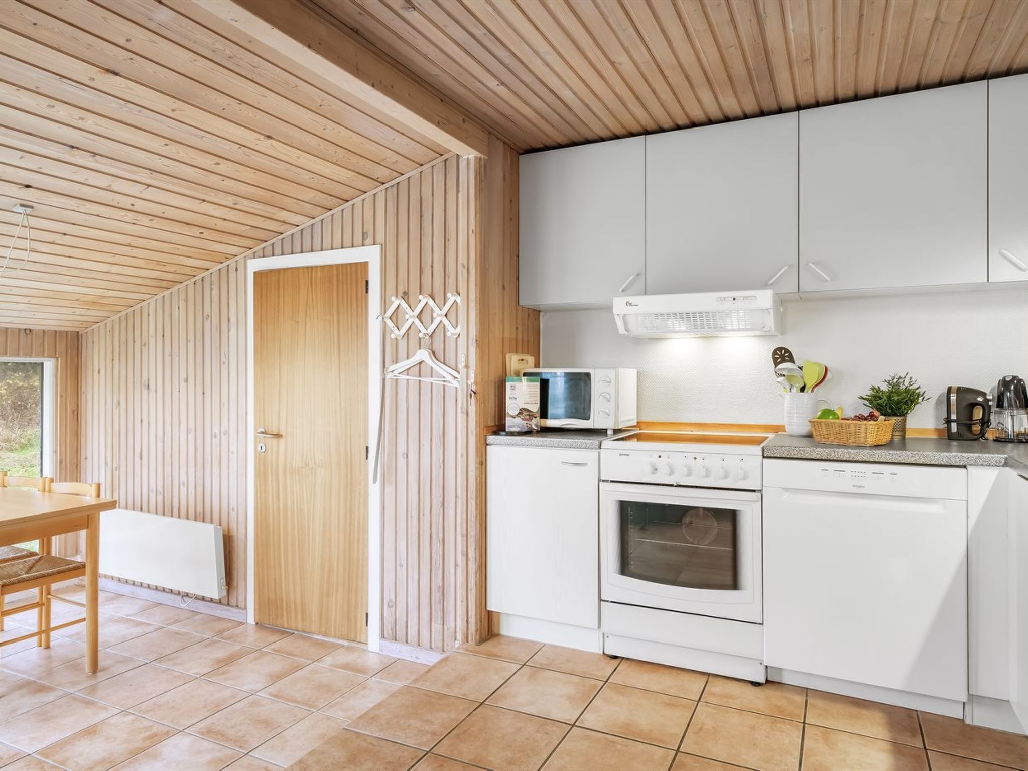 A modern kitchen with white cabinets, a built-in oven, and a microwave.