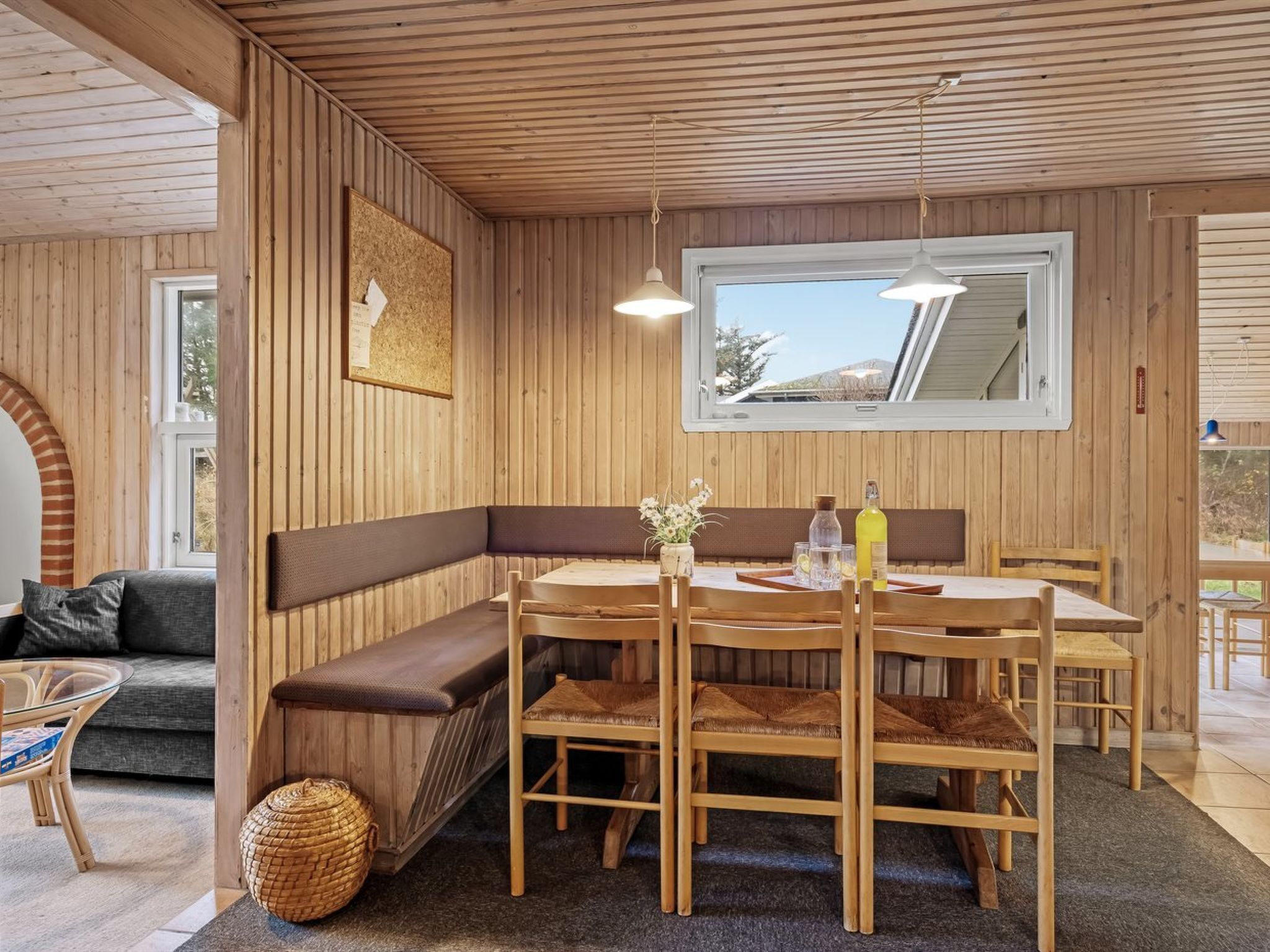 A cozy wooden interior with a dining area featuring a table, chairs, and a bench.