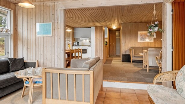 Ein Holzinterieur mit einer Couch, einem Esstisch und einer Küchenzeile.