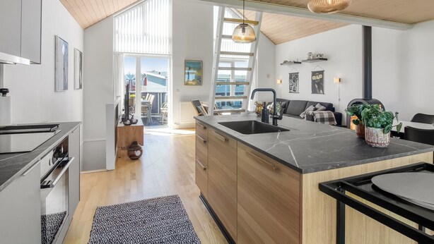 A modern kitchen with a large island, wooden cabinets, and a black countertop.