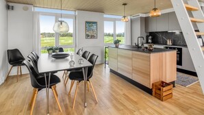A modern kitchen with a central island, black chairs, and a dining table with a view of the outdoors.