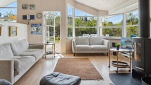 A modern living room with two sofas, a coffee table, and a fireplace. Large windows provide natural light and views of the outdoors. - "Petri" - 500m from the sea by Interhome (Hals)