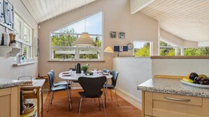 A modern kitchen with a dining area, large windows, and a view of greenery. - "Petri" - 500m from the sea by Interhome (Hals)