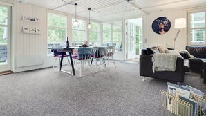 A spacious room with a dining area, a black sofa, and a large window providing natural light. - "Gunward" - 1.5km from the sea by Interhome (Sæby)