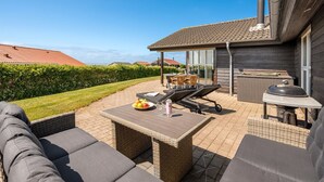 Eine Terrasse mit Gartenmöbeln, einem Grill und Blick auf die Umgebung.