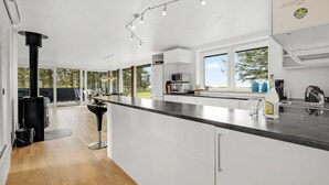 Een moderne keuken met een groot eiland, witte kasten en een zwart fornuis.