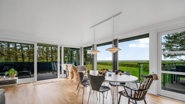 Een moderne eetruimte met een grote tafel, stoelen en hanglampen.