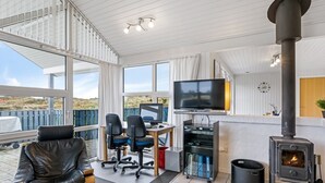 A modern living room with a large TV, comfortable seating, a fireplace, and a view of the outdoors. - "Gottfreda" - 330m to the fjord by Interhome (Hvide Sande)