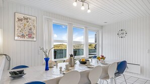 A dining area with a white table, blue chairs, and a view of the outdoors. - "Gottfreda" - 330m to the fjord by Interhome (Hvide Sande)
