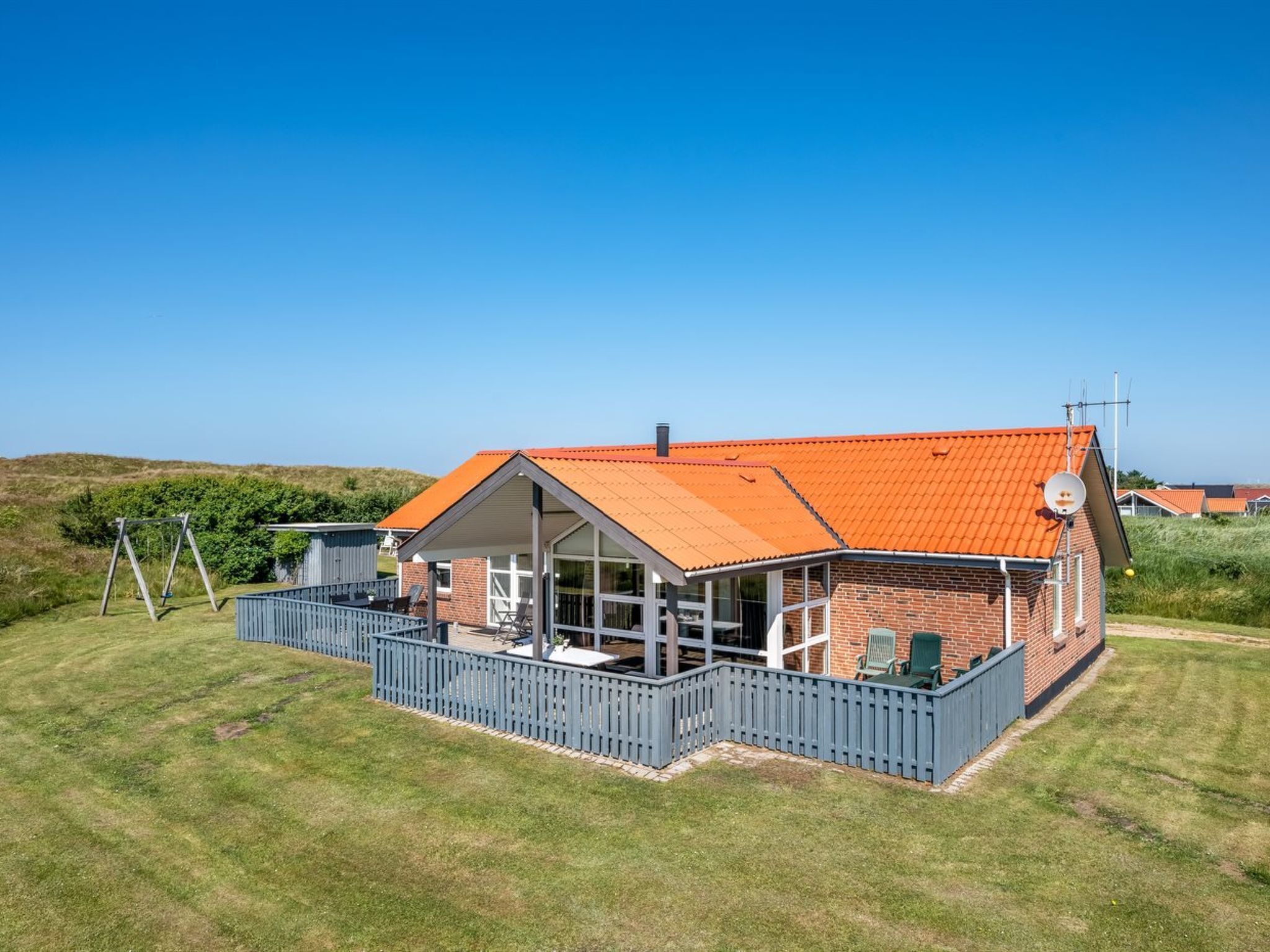 Ein Haus mit rotem Dach, umzäunter Veranda und Satellitenschüssel.