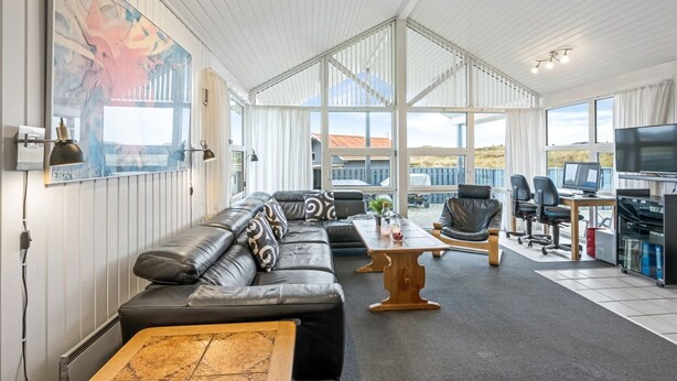 A spacious living area with a large sofa, a coffee table, and a TV area with multiple screens. - "Gottfreda" - 330m to the fjord by Interhome (Hvide Sande)