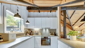 A modern kitchen with white cabinetry, a built-in oven, and pendant lighting. - "Sidse" - 400m from the sea by Interhome (Ringkøbing)