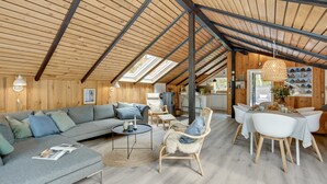 A spacious loft with a high ceiling, wooden beams, a grey sofa, a dining table with chairs, and a kitchen area. - "Sidse" - 400m from the sea by Interhome (Ringkøbing)