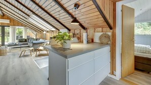 A modern interior with a wooden ceiling, a central island with a plant, and a view of an outdoor area. - "Sidse" - 400m from the sea by Interhome (Ringkøbing)