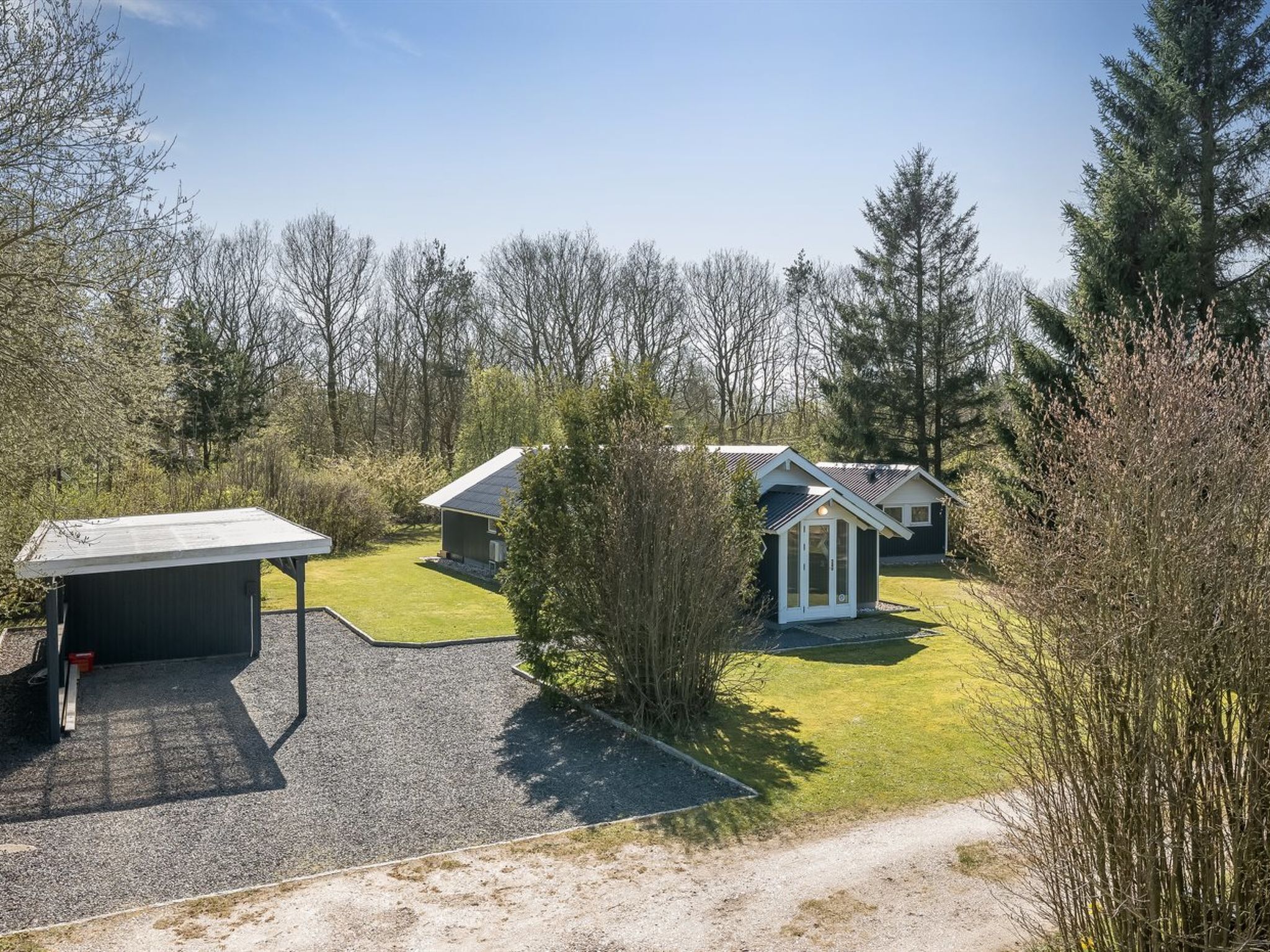 A residential property with a covered outdoor area, a small house, and a well-maintained lawn.
