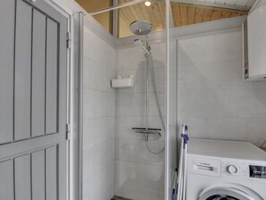 Een kleine badkamer met een douche, een wasmachine en een toilet.