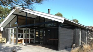 A modern building with large windows, a wooden deck, and a chimney. - "Alin" - 600m from the sea by Interhome (Oksbøl)