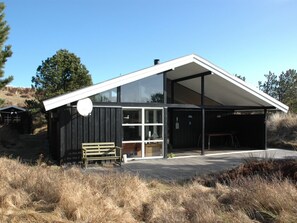 Een modern, gelijkvloers gebouw met een grote glazen deur en een overdekte veranda.