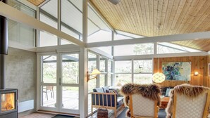 A spacious living area with a fireplace, large windows, and a high ceiling. - "Alin" - 600m from the sea by Interhome (Oksbøl)